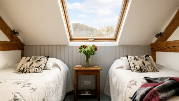 Two single beds with bedside lights and skylights in the Mid Wales holiday lodge