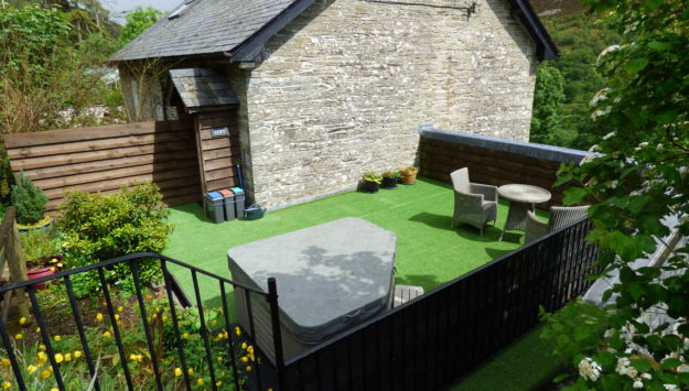 The garden of the couples cottage with a hot tub covered over